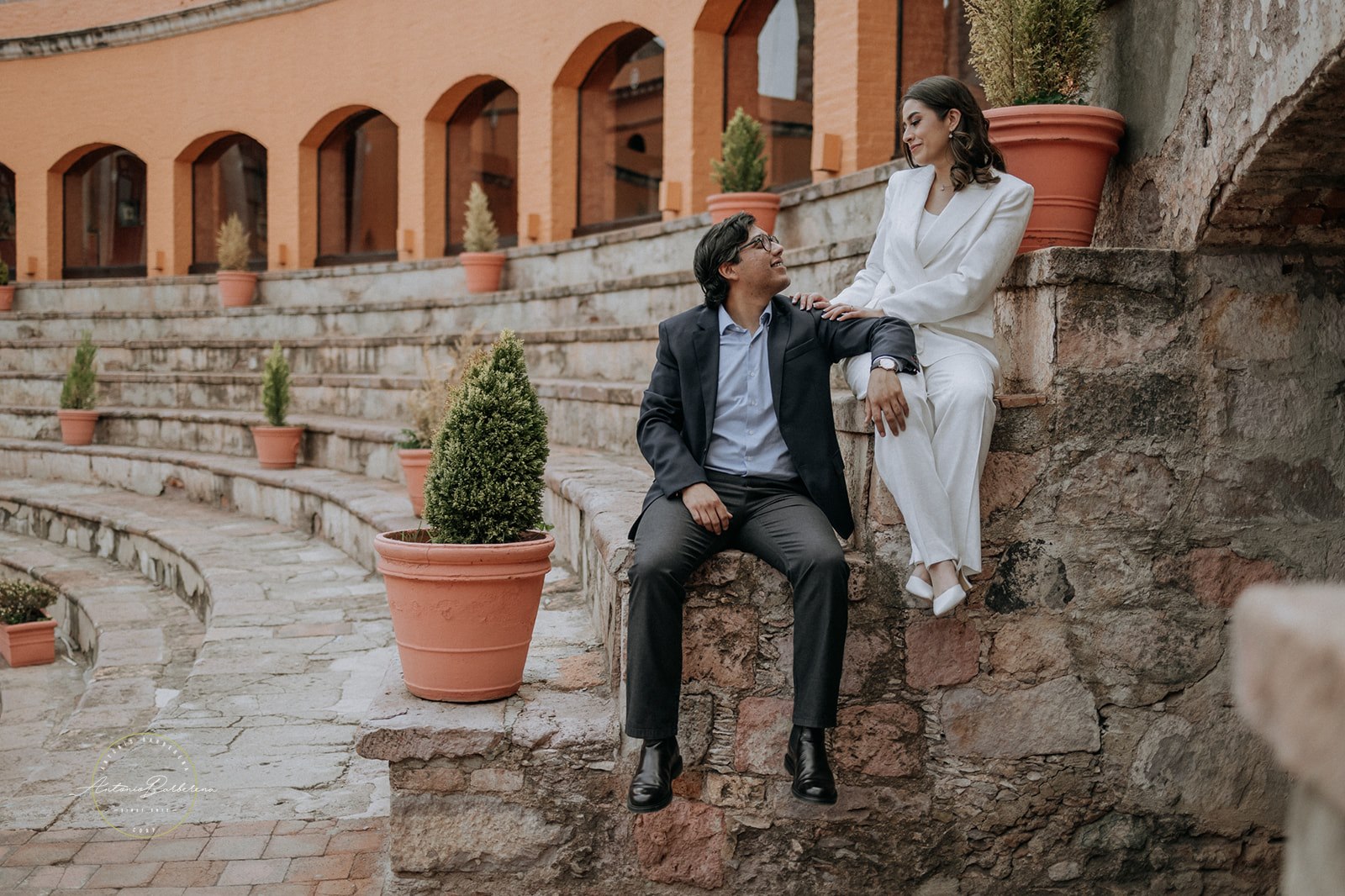 Pareja sentada en escalones de piedra en patio colonial