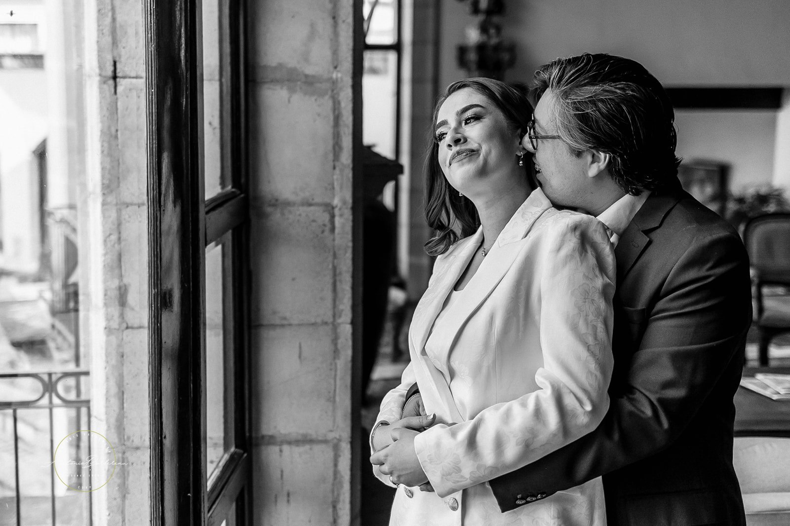 Abrazo íntimo junto a ventanas grandes, blanco y negro